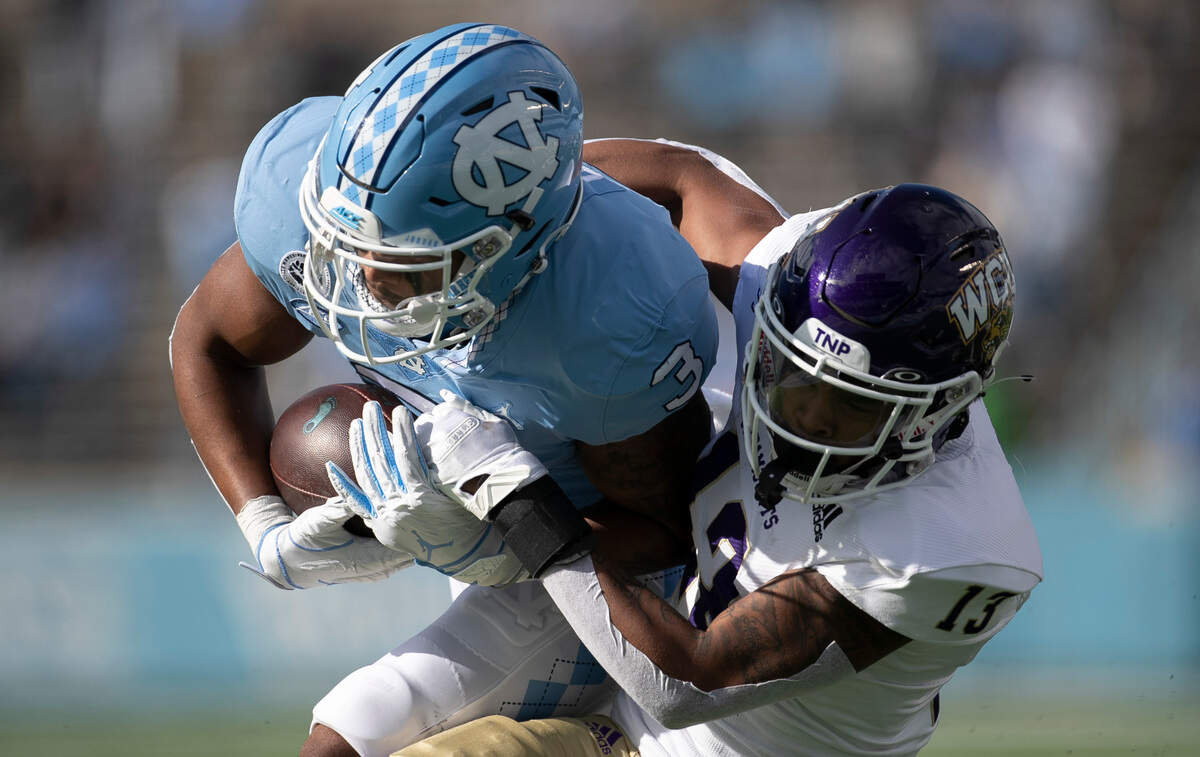 North Carolina’s Antoine Green (3) scores on a 22-yard pass completion from quarterback Sam Howell as Western Carolina’s Ronald Kent Jones (13) tries to stop him at the goal line in the first quarter to give the Tar Heels’ a 14-3 lead on Saturday, December 5, 2020 at Kenan Stadium in Chapel Hill, N.C.
