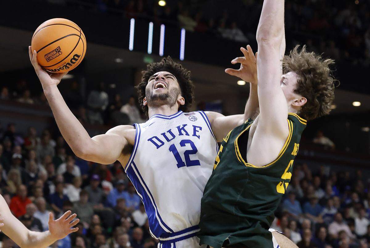 Duke’s Cameron Boozer (12) drives to the basket as Siena’s Riley Mulvey (55) defends during the second half of Duke’s 71-65 victory over Siena in the first round of the NCAA Men’s Basketball Tournament at  Bon Secours Wellness Arena in Greenville, S.C., Thursday, March 19, 2026.
