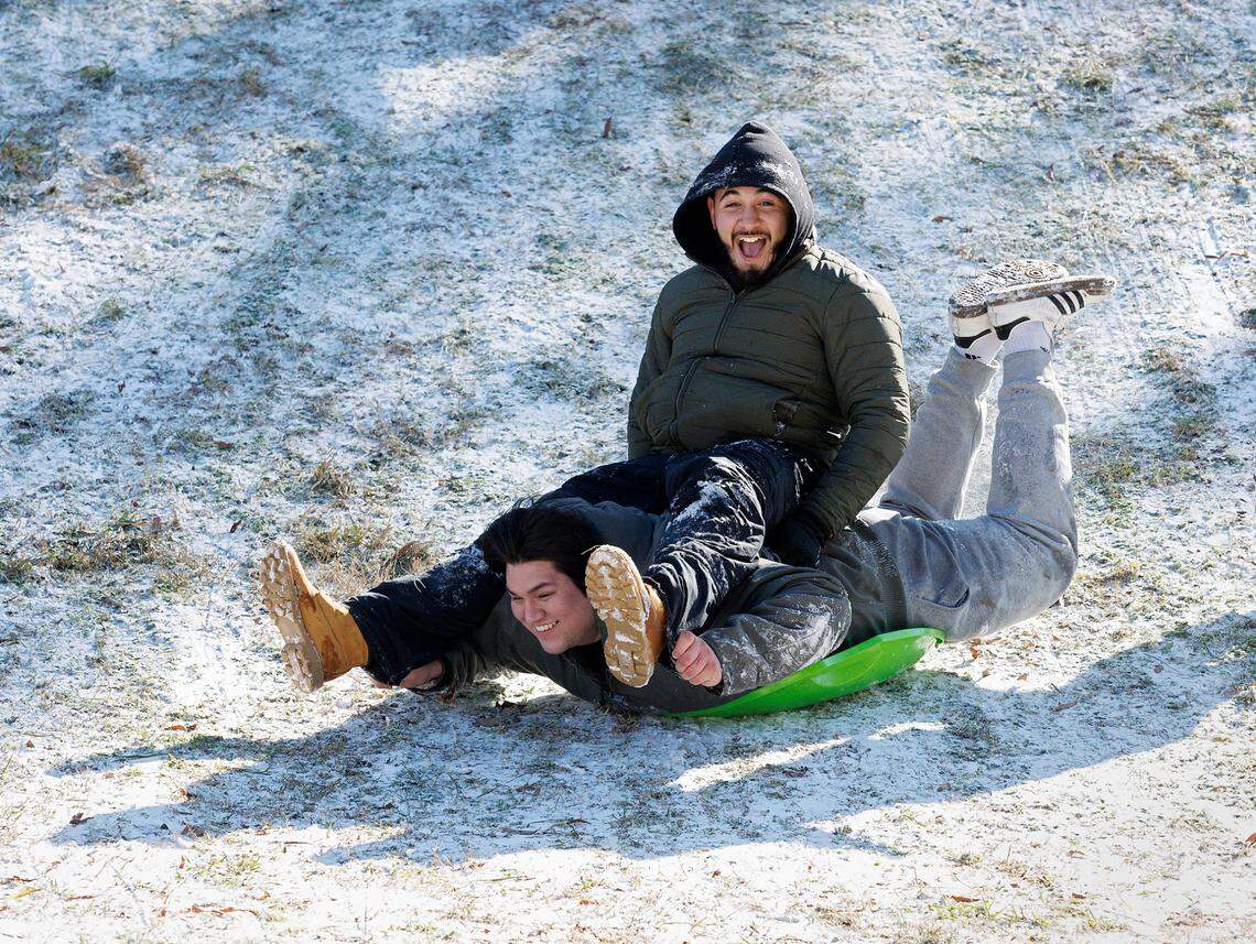 Israel Flores and Fidel Albiter sled down a hill at Bond Park on Wednesday, Jan. 22, 2025, in Cary, N.C.