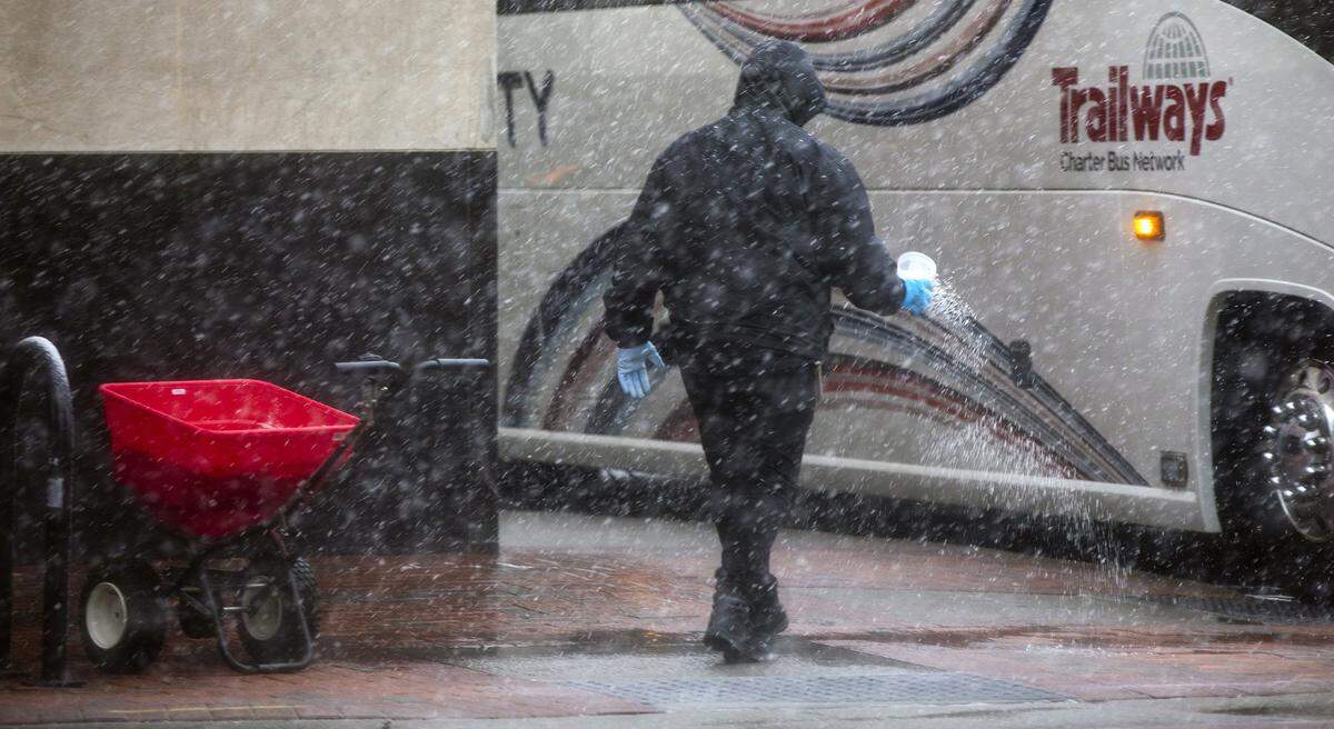 Nolan Torres, from Anchorage, A.K., spreads salt on the sidewalk in front of the 21c Museum Hotel as snow begins to fall on Thursday, Feb. 20, 2020, in Durham, N.C.