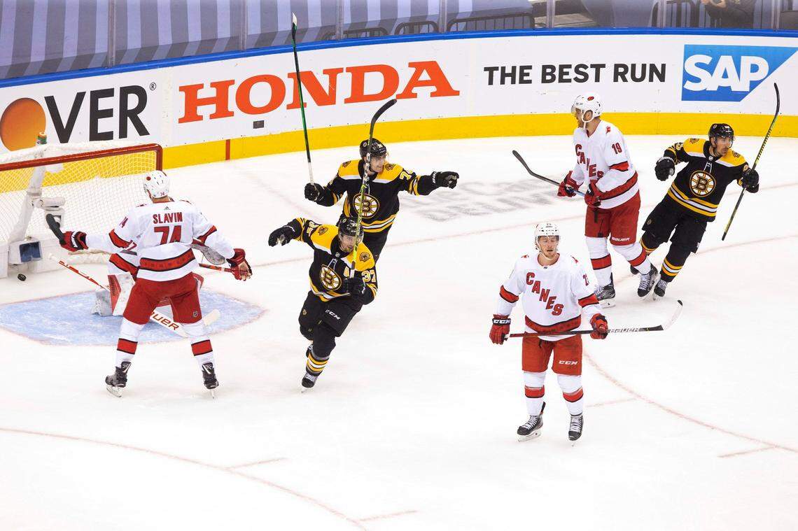 Carolina Hurricanes’ Brock McGinn (23) Dougie Hamilton (19) and Jaccob Slavin (74) react as Boston Bruins’ Patrice Bergeron (37), Jake DeBrusk (74) and Brad Marchand (63) celebrate David Krejci’s goal during the first period of an NHL Eastern Conference Stanley Cup hockey playoff game in Toronto, Thursday, Aug. 13, 2020. (Chris Young/The Canadian Press via AP)