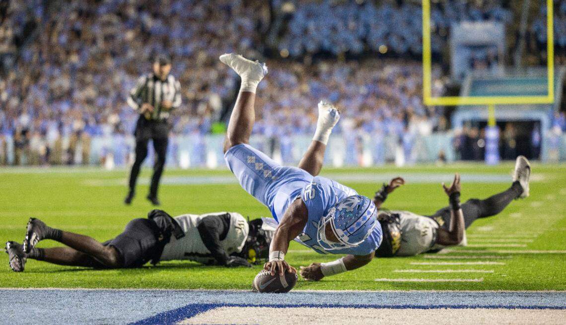 North Carolina quarterback Jacolby Criswell (12) dives over Wake Forest defensive back Zamari Stevenson (17) to score on a 4-yard run to give the Tar Heels a 7-3 lead in the second quarter on Saturday, November 16, 2024 at Kenan Stadium in Chapel Hill, N.C.
