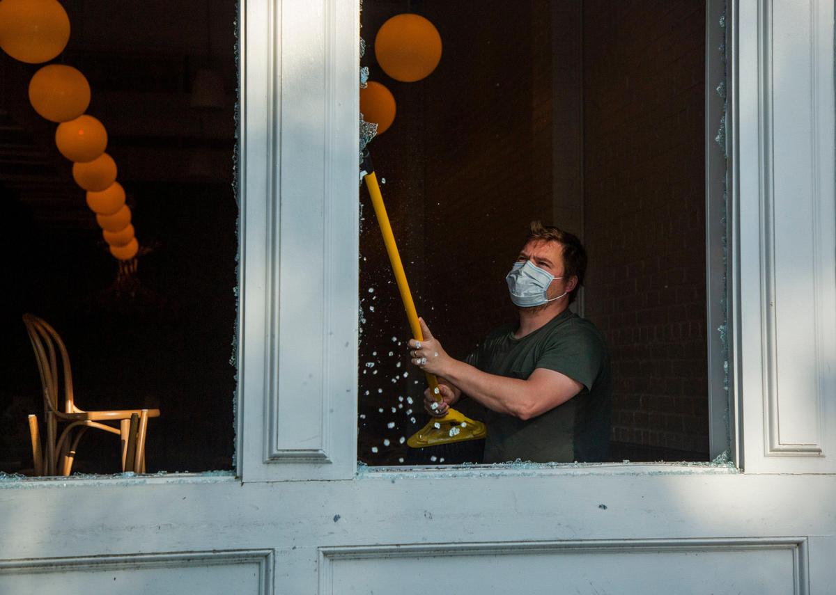 Patrick Woodson, co-owner of Brewery Bhavana, clears the remaining glass on his windows that were vandalized Saturday night by protestors gathered in response to the death of George Floyd in the custody of Minneapolis Police on Monday, joining protestors in major cities across the country, on Sunday, May 31, 2020, in Raleigh, N.C.