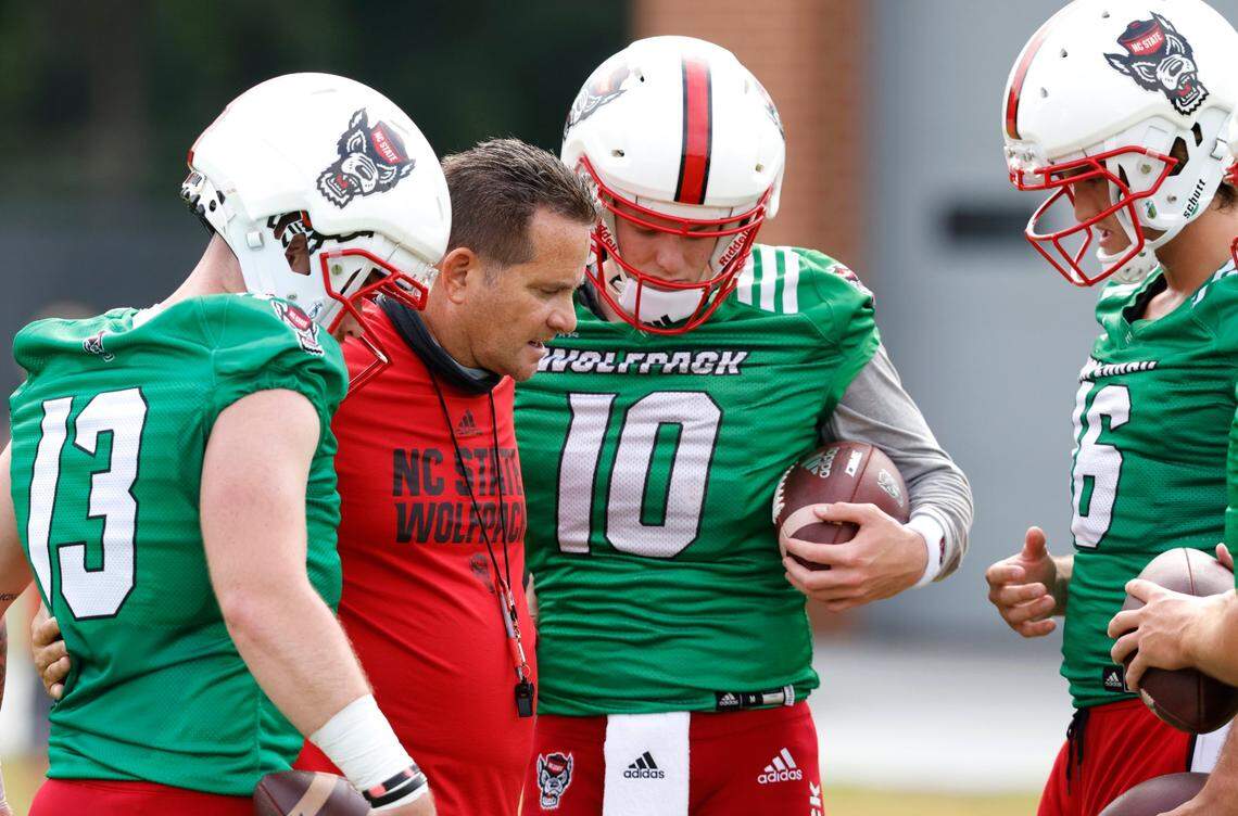 N.C. State offensive coordinator Tim Beck talks with quarterbacks Devin Leary (13), Ben Finley (10) and Aaron McLaughlin (16) during the Wolfpacks first practice of fall camp in Raleigh, N.C., Wednesday, August 4, 2021.
