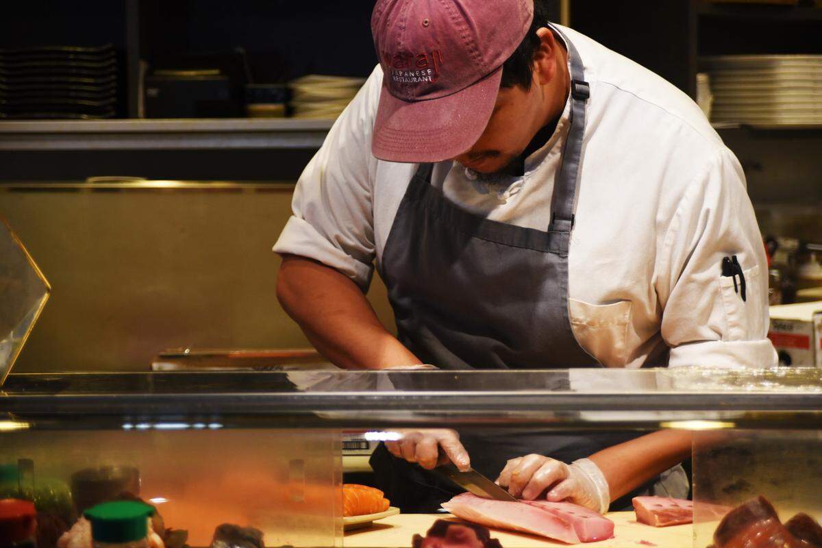 Waraji sushi chef Jorge Hernandez carefully butchers fish prior to opening for lunch service.