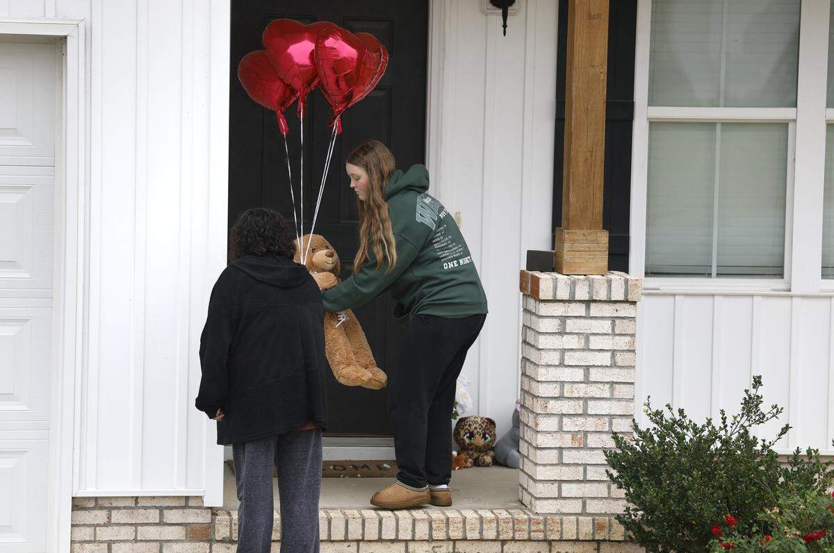 Rachel Ross sets a teddy bear and four balloons on the porch of the home of Wellington Dickens III in Zebulon, N.C., Wednesday, Oct. 29, 2025. Dickens faces four charges of murder in the deaths of his children 6-year-old Leah Dickens, 9-year-old Zoe Dickens, 10-year-old Wellington Dickens IV and 18-year-old Sean Brasfield, his stepson.