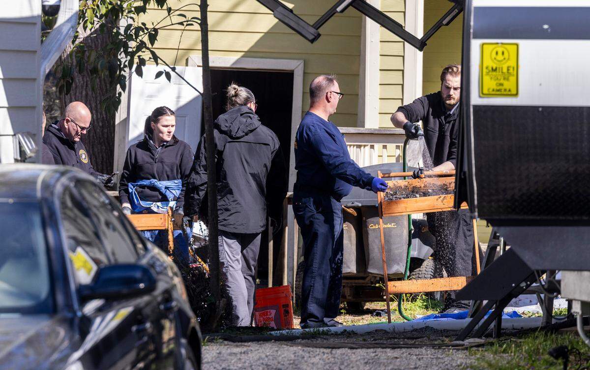 Investigators sift through charred debris Monday, March 20, 2023 after human remains were found in a fire pit outside a home under renovation in Cary on Sunday. A critically injured man was found in an RV on the property with a self-inflicted gunshot wound.