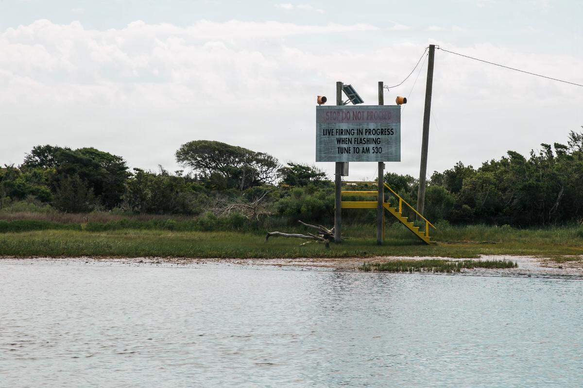 A warning sign stands near Browns Island on Marine Corps Base Camp Lejeune, North Carolina, May 14, 2026. Browns Island remains strictly off-limits due to ongoing live-fire training exercises and the presence of dangerous unexploded ordnance. All personnel accessing the island must be accompanied by an explosive ordnance disposal technician due to extreme dangers associated with the high-hazard impact area. For safety reasons, anchoring, disembarking, or engaging in bottom-disturbing activities are strictly prohibited on Browns Island and the surrounding waters.