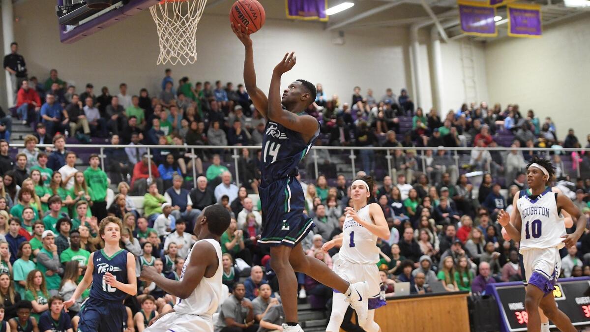 Deon Daniels (14) of Leesville Road scores a basket against DJ Thomas, second from left, Penn Sealey (1) and Naikeed Thomas (10) of Broughton. The Leesville Road Pride played the Broughton Capitals in a high school men basketball game on February 22, 2019.