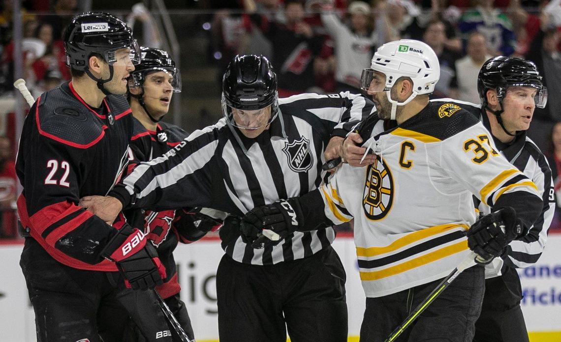 Officials separate Carolina Hurricanes’ Brett Pesce (22) and Boston Bruins’ Patrice Bergeron (37) in the first period on Wednesday, May 4, 2022 during game two of their Stanley Cup first round series at PNC Arena in Raleigh, N.C.