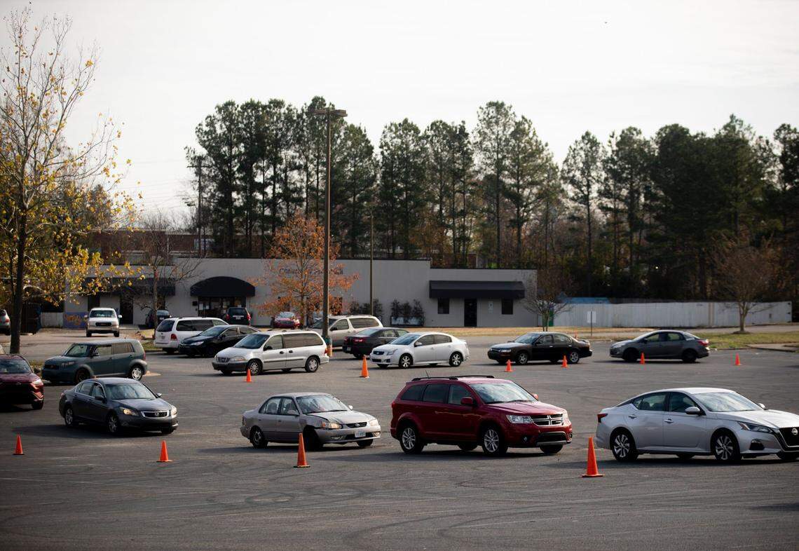 People waiting inside their cars line up around the parking lot of the Lakewood Shopping Center to receive food from the Durham Community Food Pantry, on Wednesday, Dec. 9, 2020, in Durham, N.C.