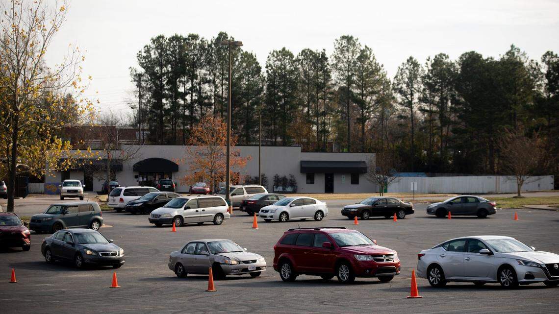 People waiting inside their cars line up around the parking lot of the Lakewood Shopping Center to receive food from the Durham Community Food Pantry, on Wednesday, Dec. 9, 2020, in Durham, N.C.