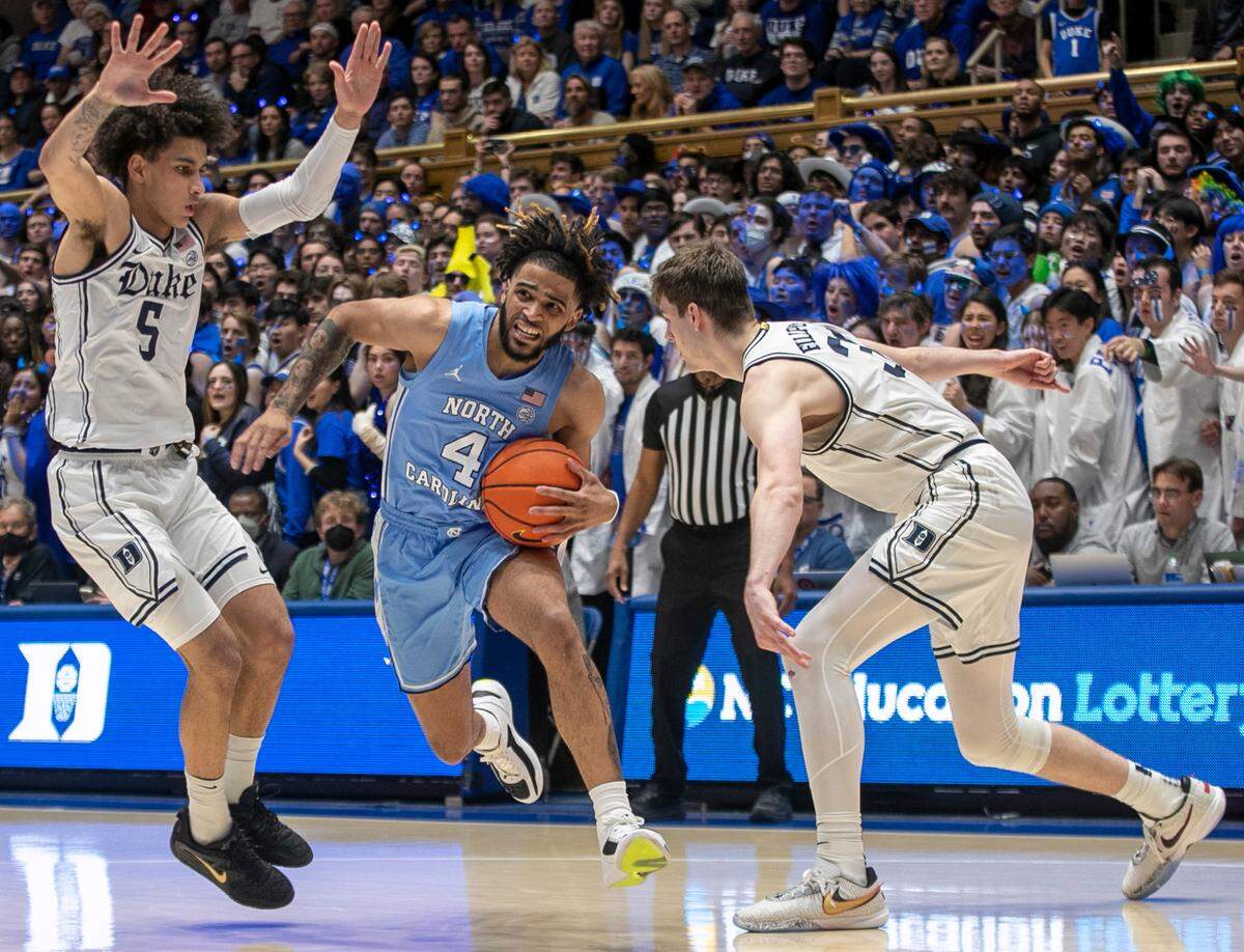 North Carolina’s R.J. Davis (4) drives to the basket between Duke’s Tyrese Proctor (5) and Kyle Filipowski (30) in the second half on Saturday, February 4, 2023 at Cameron Indoor Stadium in Durham, N.C.