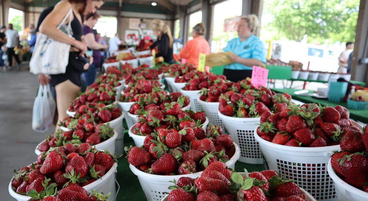 A customer buys strawberries from Penny’s Produce at the State Farmers Market in Raleigh, N.C. on May 1, 2022.