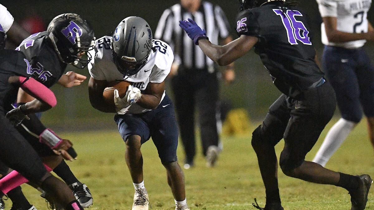 Hillside running back Christian Cook (22) runs for yardage between Riverside’s JayShawn Wiley (16) and Chesden Seal (26) during the first half. The Durham Hillside Hornets and the Durham-Riverside Pirates met in a football game in Durham. N.C. on October 4, 2024.