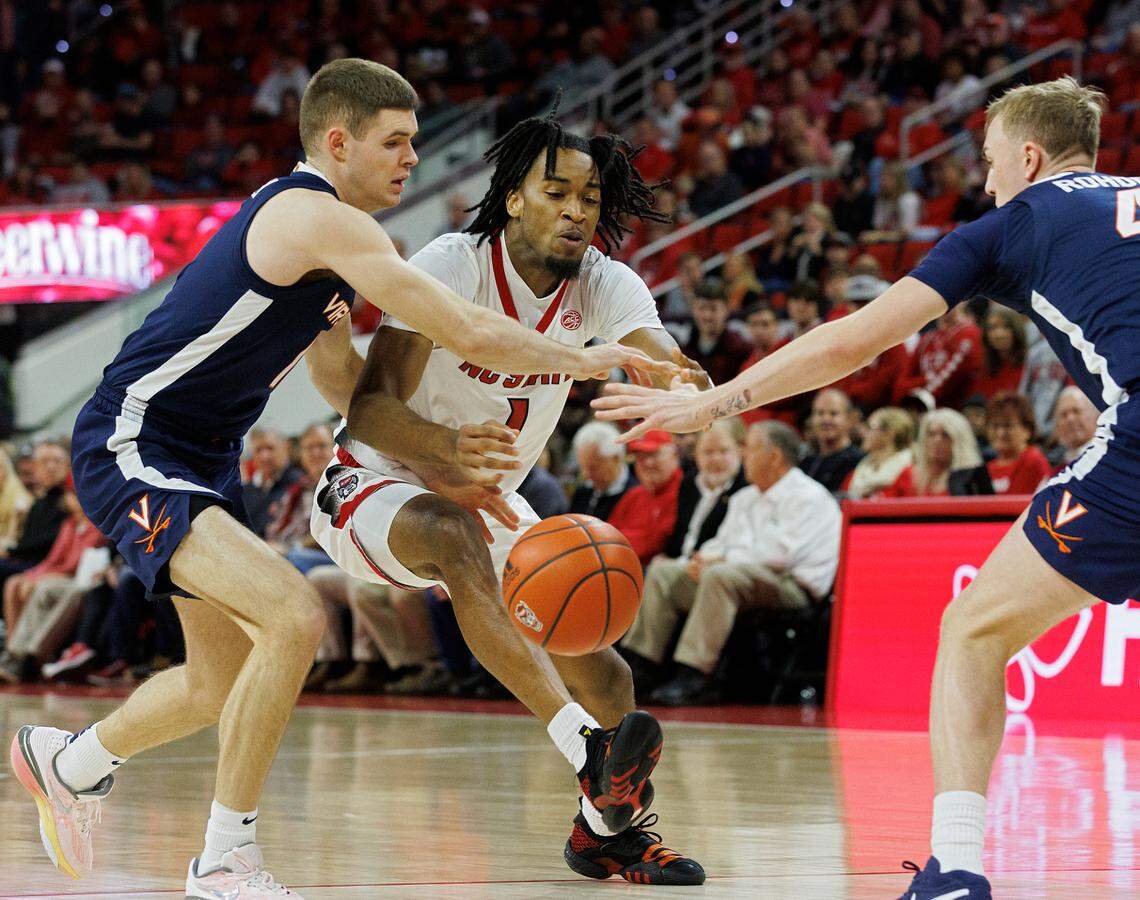 N.C. State’s Jayden Taylor drives between Virginia’s Isaac McKneely and Andrew Rohde during the first half of the Wolfpack’s game on Saturday, Jan. 6, 2024, at PNC Arena in Raleigh, N.C.