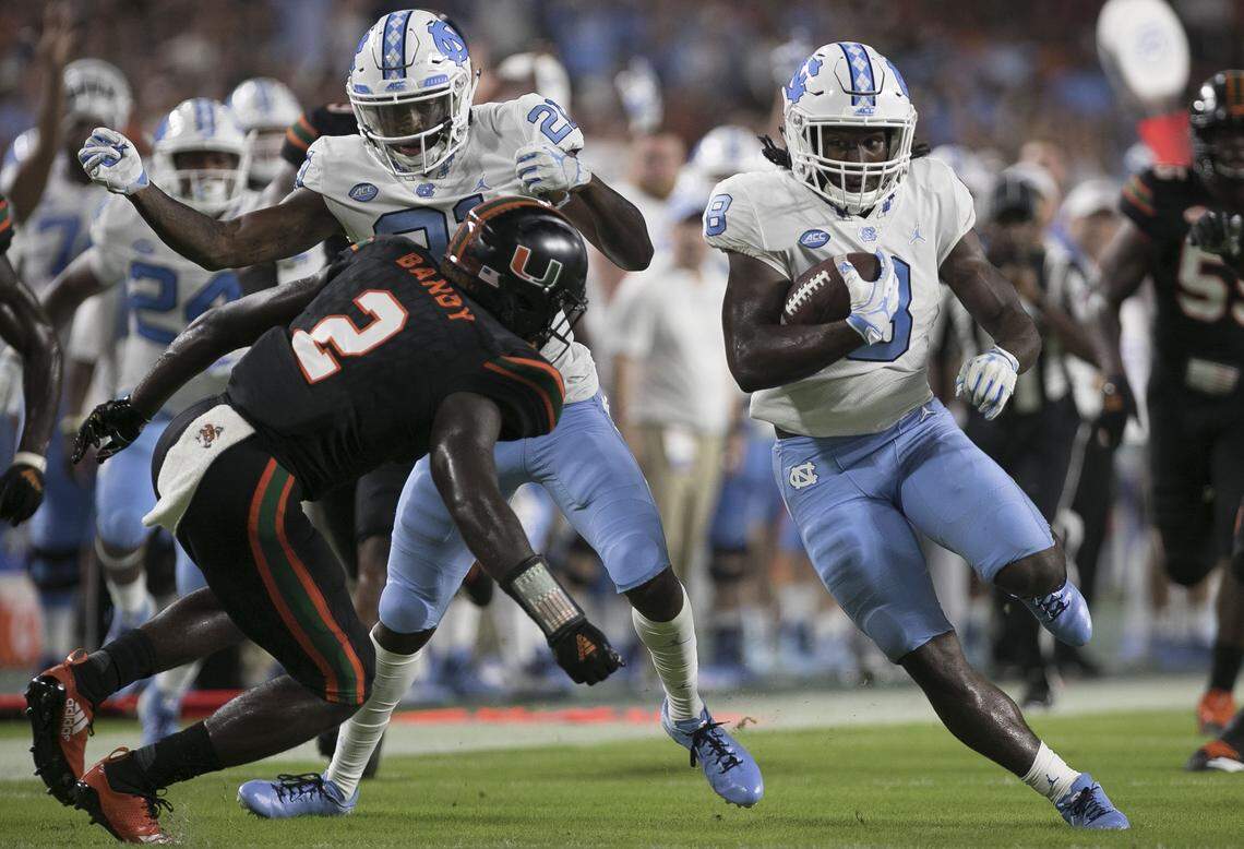 North Carolina’s Michael Carter (8) picks up 22 yards in the first quarter against Miami’s Trajan Bandy (2) on Thursday, September 27, 2018 at Hard Rock Stadium in Miami Gardens, Florida.