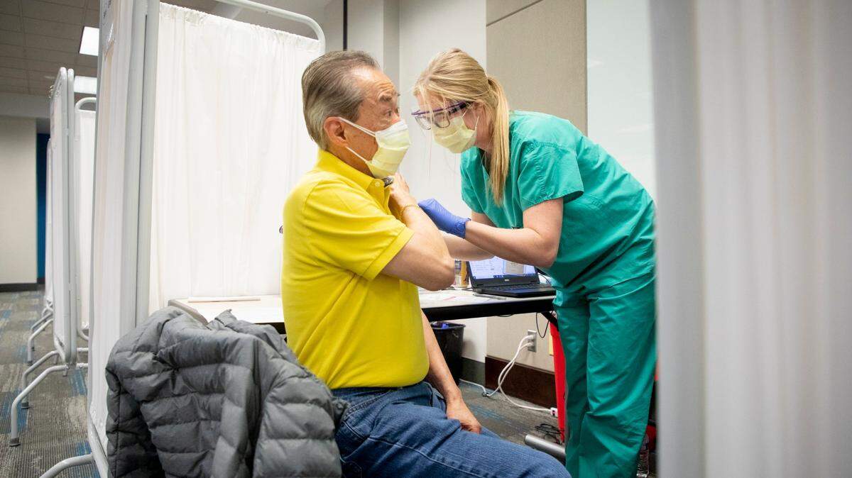 Kwan Cheung, left, receives his first dose of the Moderna COVID-19 vaccine, from Lindsay Bradshaw, a physician assistant student, at at UNC Healthcare on Jan. 14, 2020, in Chapel Hill, N.C.