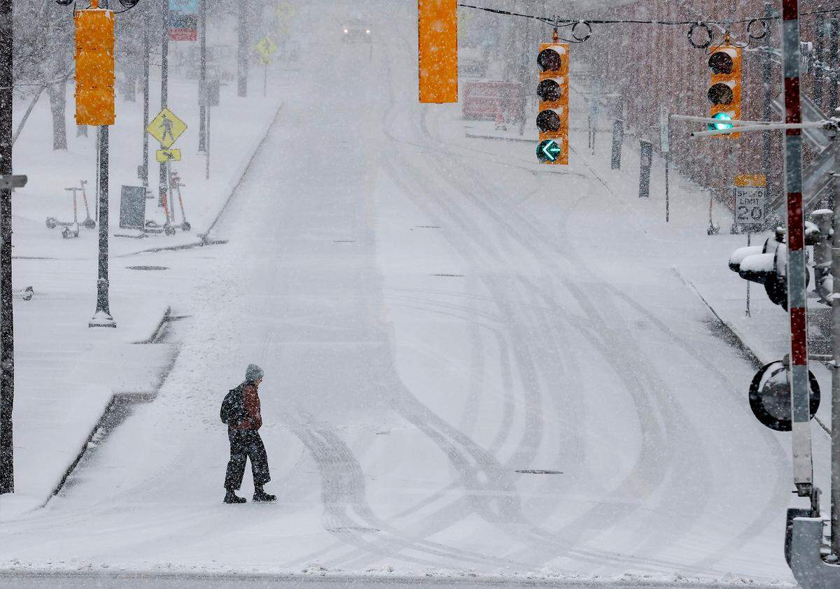 A person crosses Blackwell Street as snow falls in Durham, N.C. on Wednesday, Feb. 19, 2025.