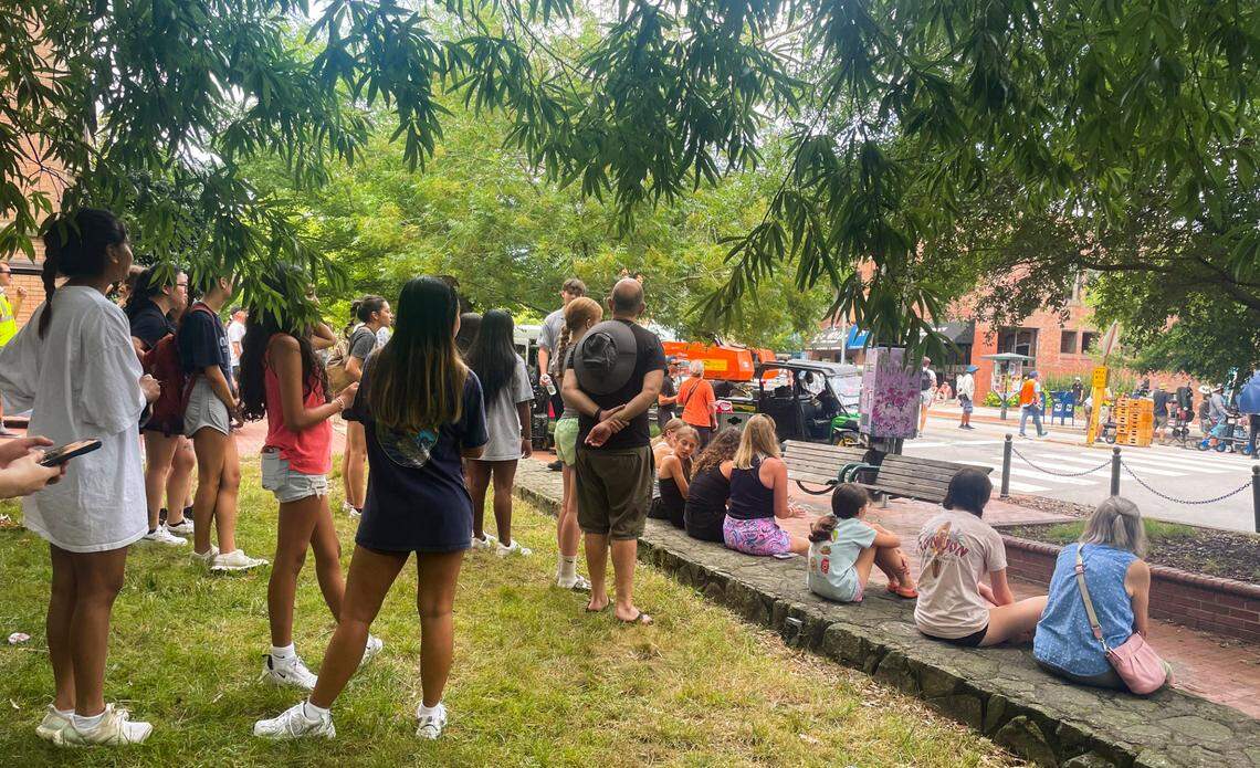 About 25 people have gathered on McCorkle Place to watch Lola Tung and Christopher Briney film a scene where they get into a car on Franklin St. on Monday, July 8, 2024.