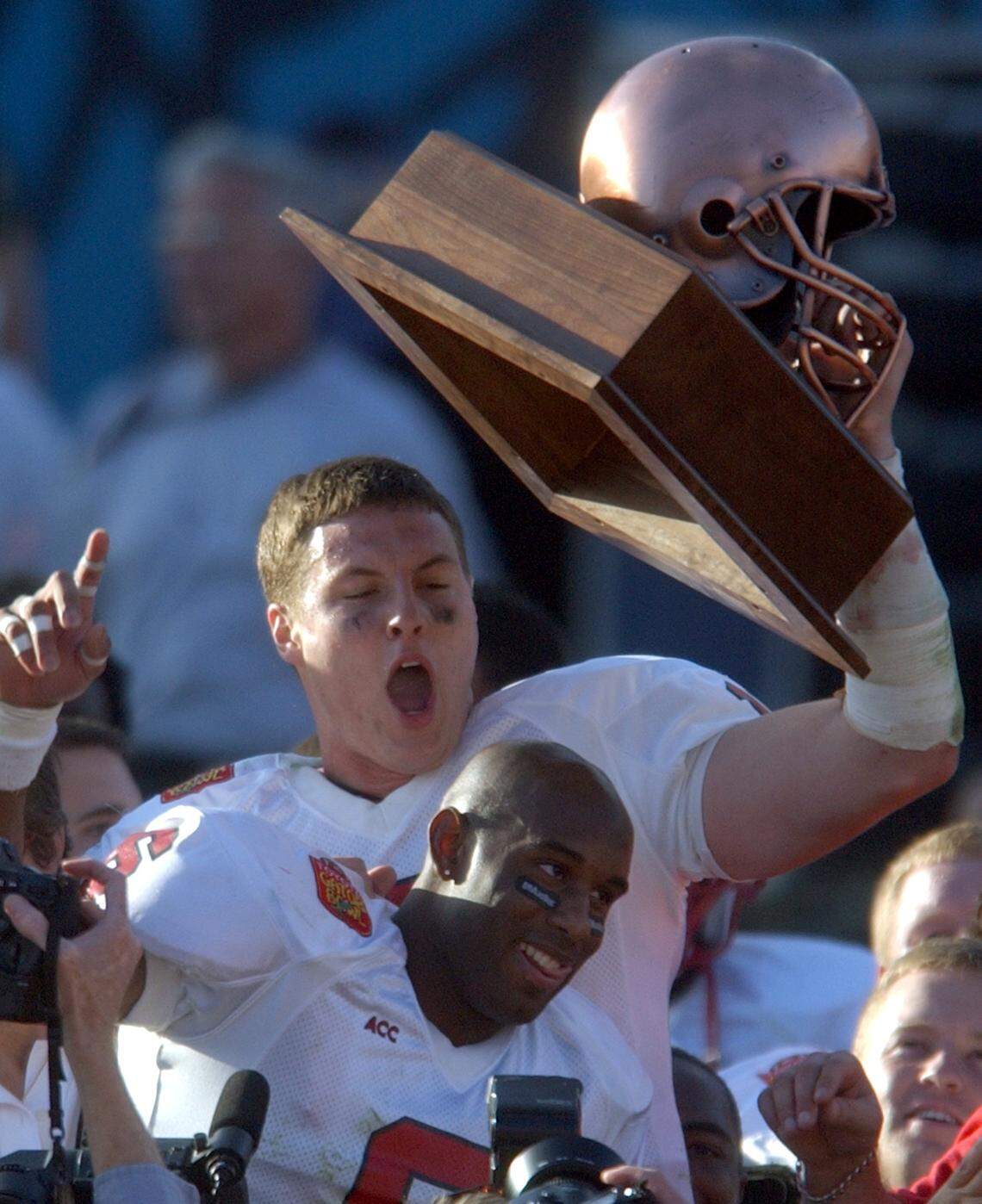 N.C. State’s Philip Rivers and Rod Johnson celebrate with Rivers’ MVP trophy after the Gator Bowl at Alltel Stadium in Jacksonville, Florida in January 2003.