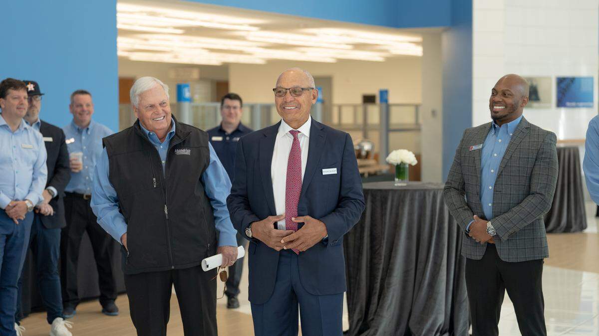 Rick Hendrick (left) and Reggie Jackson (center) speak at the opening of Jackson’s new Raleigh dealership while General Manager Shaye Johnson looks on.