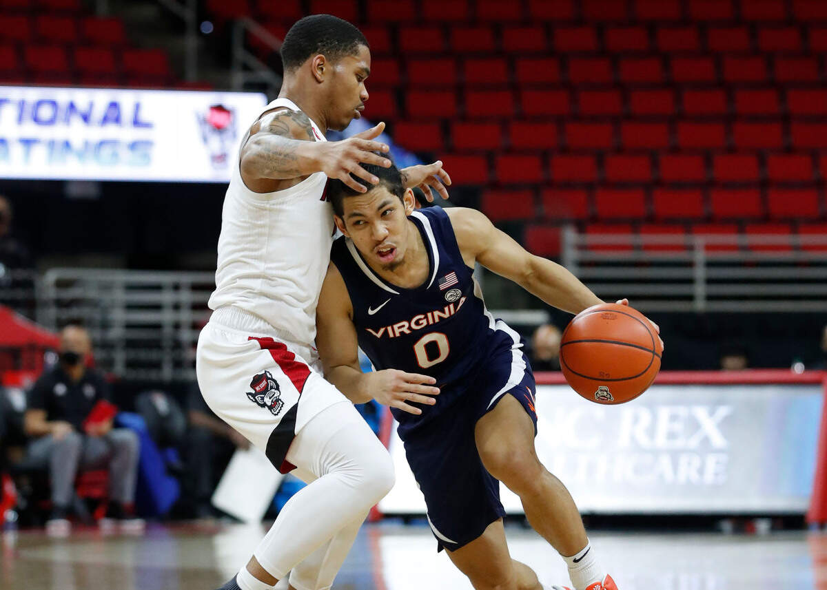 Virginia’s Kihei Clark (0) drives around N.C. State’s Shakeel Moore (2) during the second half of Virginia’s 64-57 victory over N.C. State at PNC Arena in Raleigh, N.C., Wednesday, February 3, 2021.