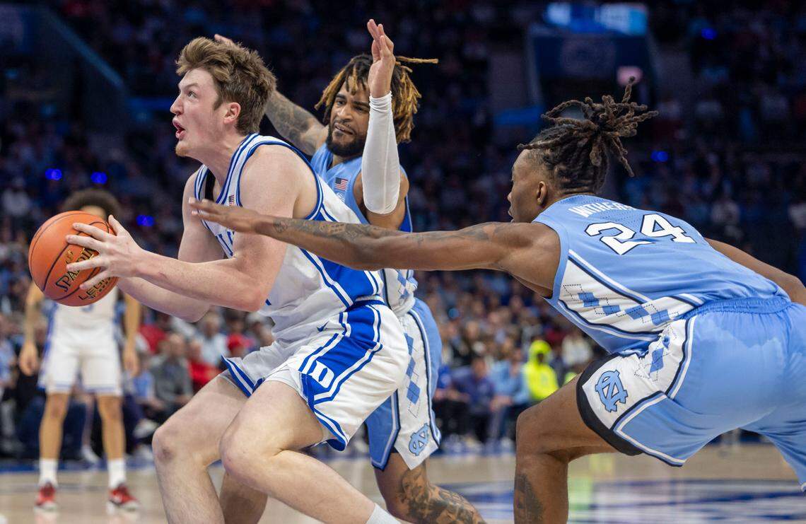 North Carolina guard R.J. Davis (4) and forward Jae’Lyn Withers (24) work to slow Duke’s Kon Knueppel (7) as he drives to the basket in the first half on Friday, March 14, 2025 during the semifinals of the ACC Tournament at Spectrum Center in Charlotte, N.C. Knueppel scored 17 points leading the Blue Devils to a 74-71 victory.