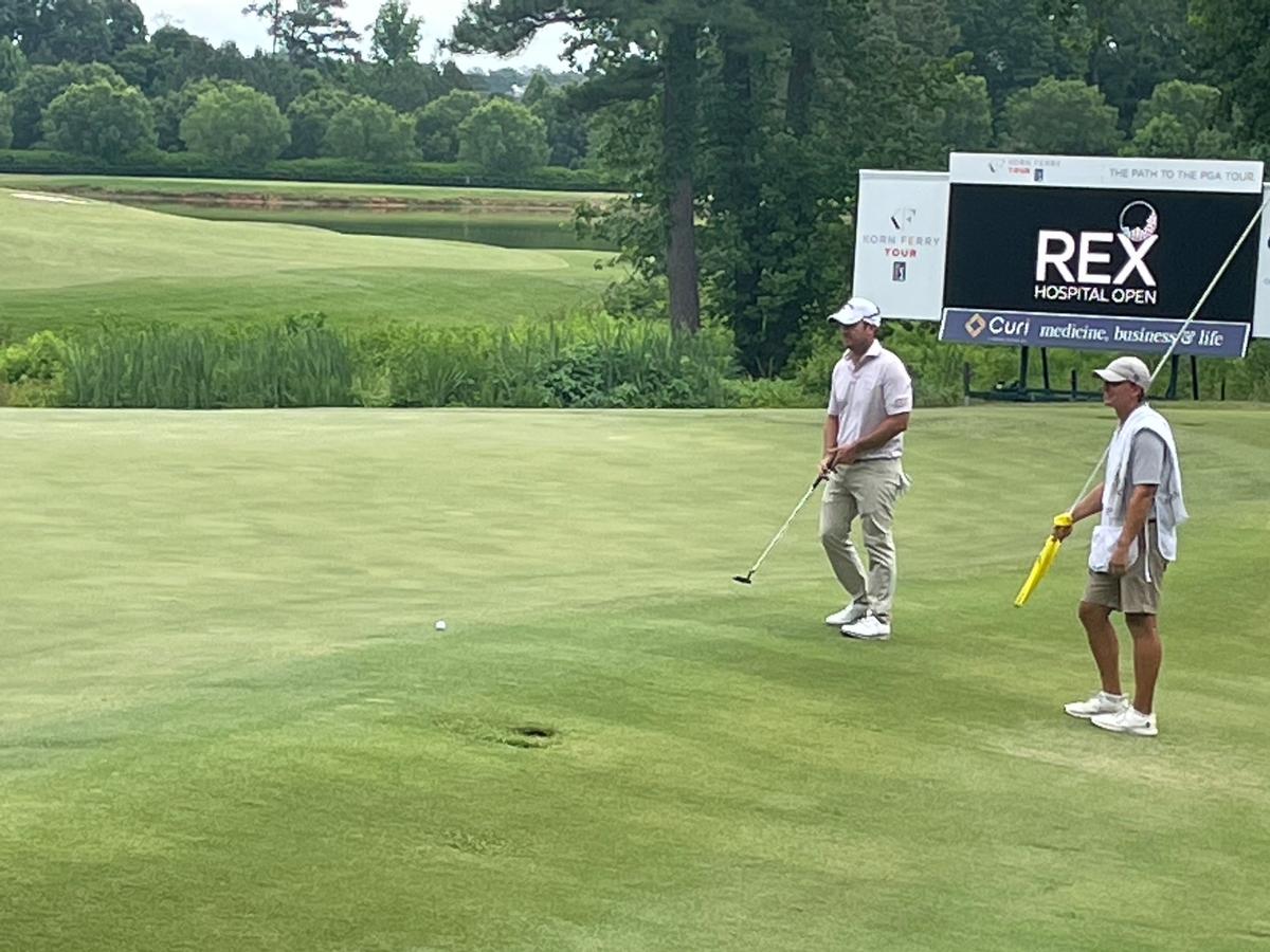 Ryan Blaum, left, sizes up a putt on the 18th green at the Country Club at Wakefield Plantation on Friday as he finishes up a 7-under-par 64 in the second round of the Rex Hospital Open.