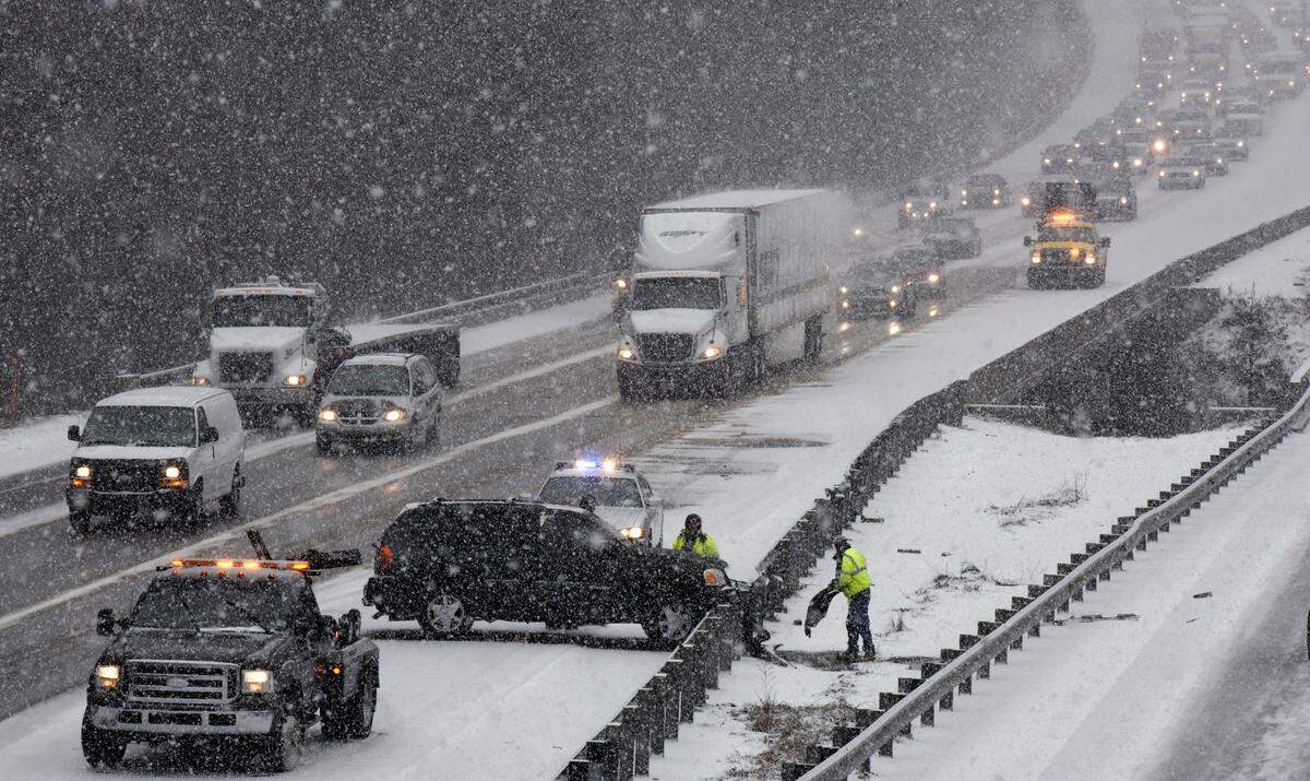 Tow truck operators try to free a vehicle from a guardrail after it slid of of westbound I-40 in Cary on Feb. 24, 2014, after early-morning snow and ice surprised many drivers on their morning commutes.
