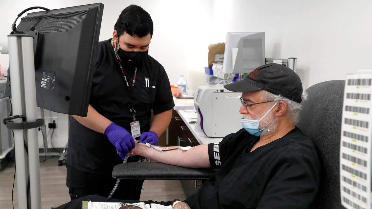 Eduardo Vargas, left, helps as Dr. Charles Gainor donates convalescent plasma at The Blood Connection in Raleigh, N.C., Monday, May 18, 2020. The four pouches of plasma donated by Gainor, a COVID-19 survivor, will be used to help treat hospitalized patients with severe cases of coronavirus.