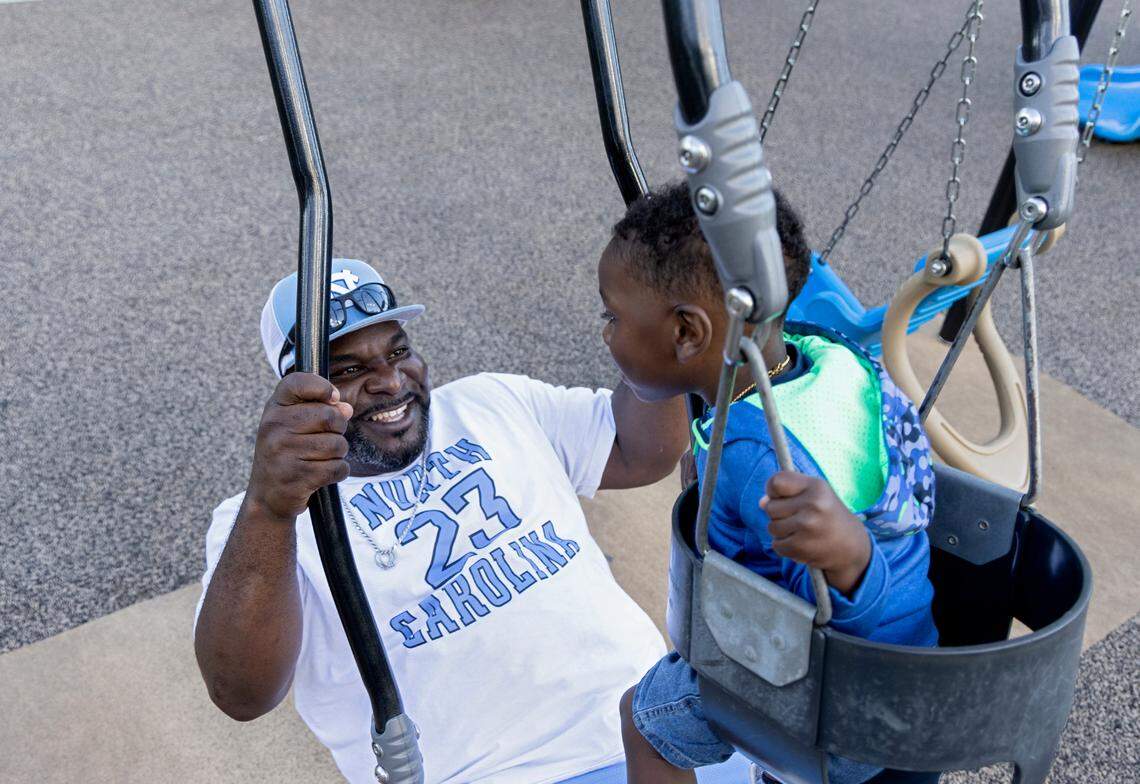 Atari Thomas smiles as he swings his youngest son, Bryson, at Barwell Road Park in Raleigh.