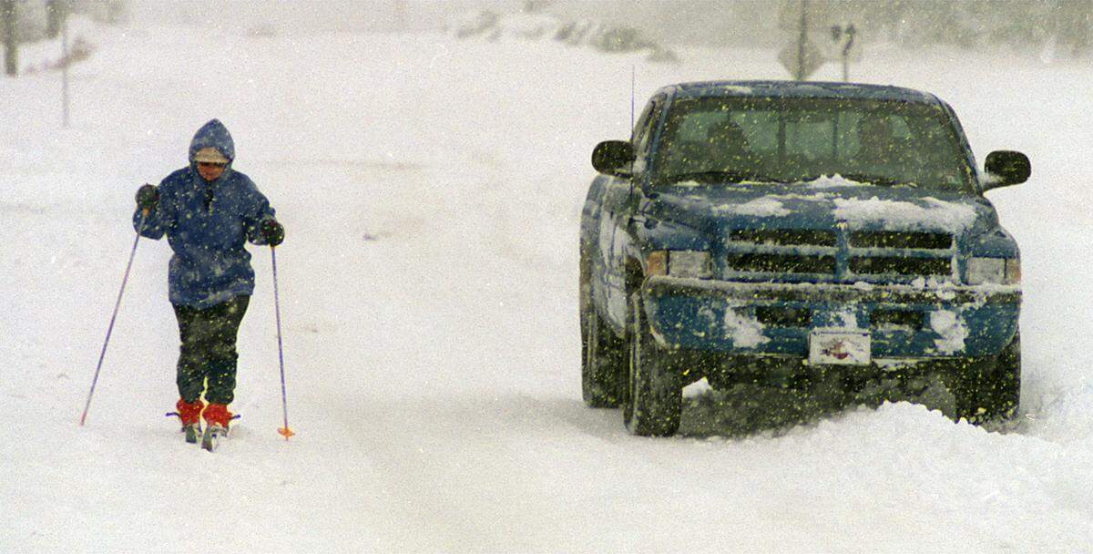A four-wheel drive pickup truck makes its way by cross-country skier Blanche Haning on Duraleigh Road in 2000.