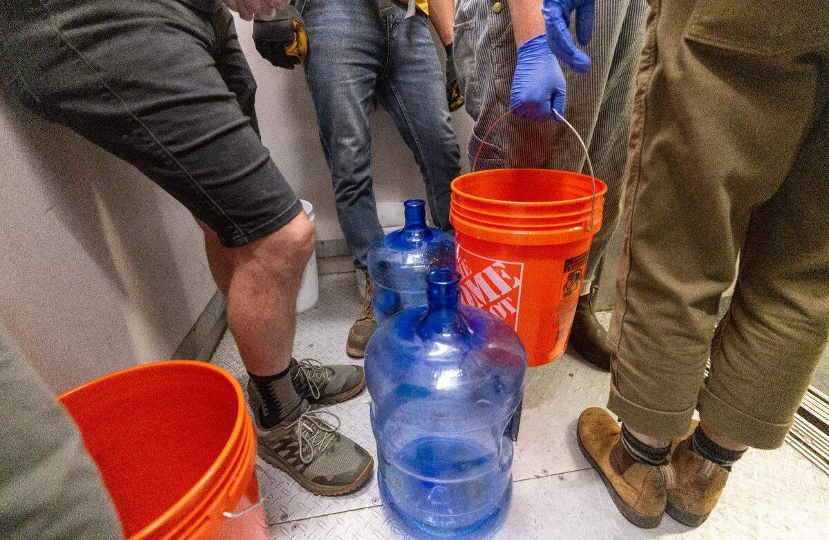 Volunteers organized by grassroots group BeLoved Asheville haul buckets of gray water to help residents in low-income independent living facilities, with no running water, flush their toilets on Wednesday, Oct. 9, 2024. About half of Asheville’s water customers were still without running water this week because the remnants of Hurricane Helene ripped apart the city’s distribution system.