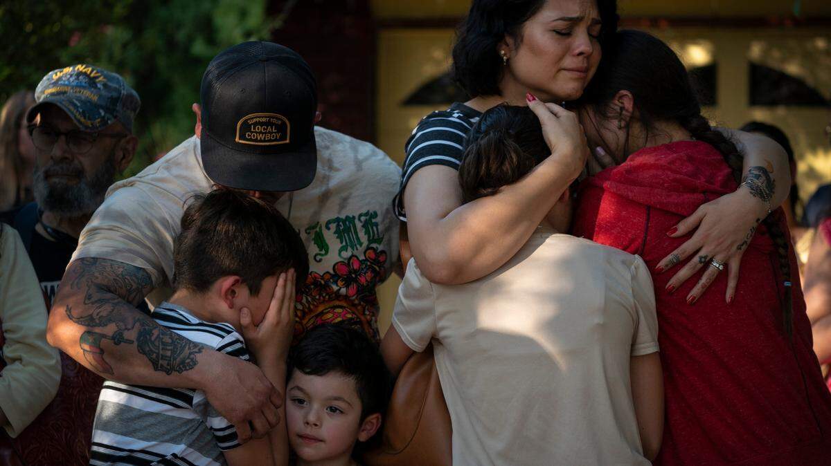 Raquel Martinez, comforts her daughters while her husband, Daniel Martinez, comforts their sons outside Robb Elementary School on May 26, 2022, in Uvalde, Texas. Martinez said her children are scared.