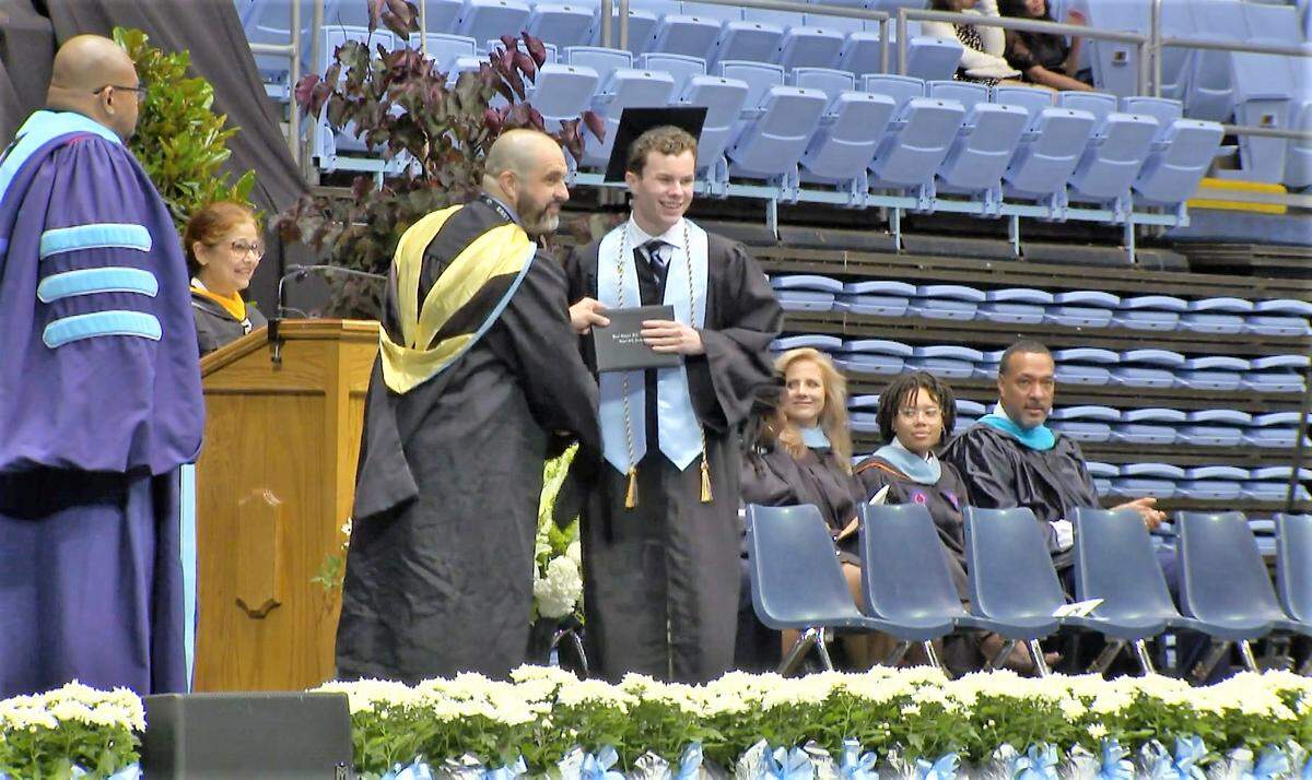 Hunter Klosty accepts his diploma cover from East Chapel Hill High School Principal Jesse Casey after calling Casey “a stupid man” during the June 10, 2023, graduation ceremony in UNC’s Smith Center in Chapel Hill.