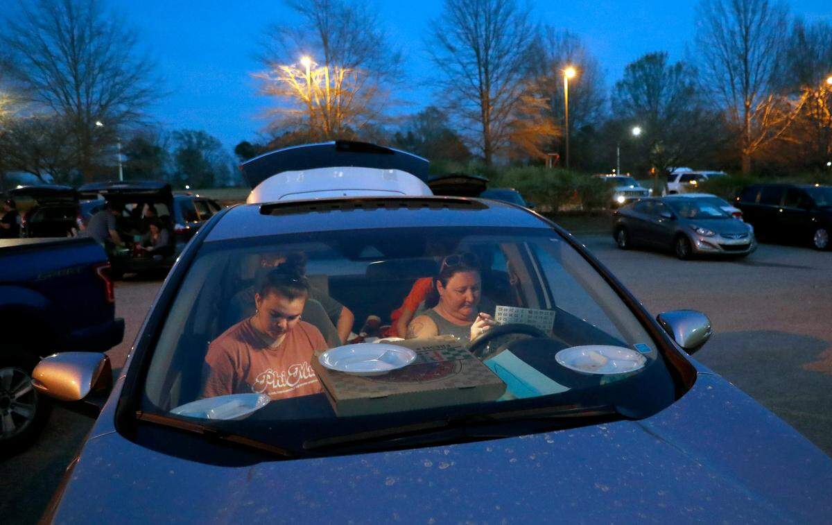 Maggie Weddle, left, and Janae Aardal fill out their bingo cards while playing parking lot bingo at Tavern on the Green at Eagle Ridge in Garner, N.C., Thursday, March 19, 2020.