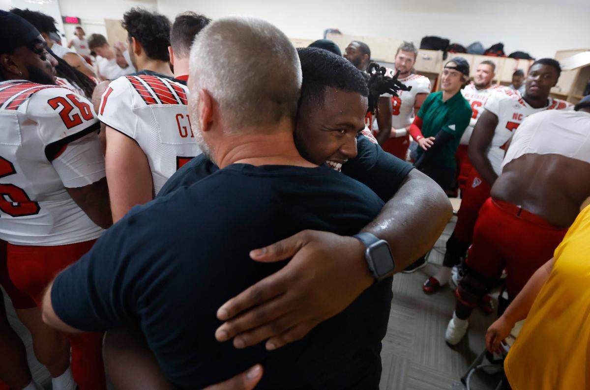 N.C. State’s Grant Gibson (50) hugs head coach Dave Doeren in the locker room after N.C. State’s 30-27 overtime victory over UNC at Kenan Stadium in Chapel Hill, N.C., Friday, Nov. 25, 2022.