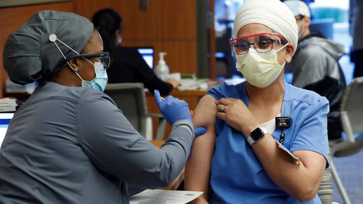 Devinder Koura, RN, gets her COVID-19 vaccine shot from Krisse Meeks, medical assistant, during a COVID vaccine clinic for employees at UNC REX Healthcare in Raleigh on Jan. 7, 2021.