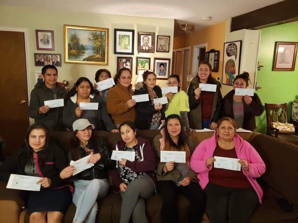 Thirteen of the workers, members of the Latino immigrant rights group Siembra NC, with checks for unpaid hours they received after reaching a settlement with their former employer.