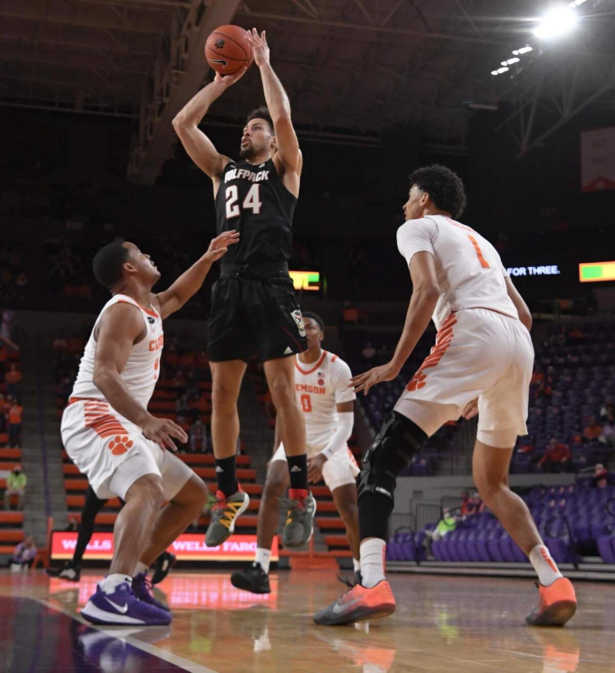 NC State guard Devon Daniels(24) shoots between Clemson sophomore guard Nick Honor(4) and Clemson senior forward Jonathan Baehre(1) during the first half of their game on Jan. 5, 2021.