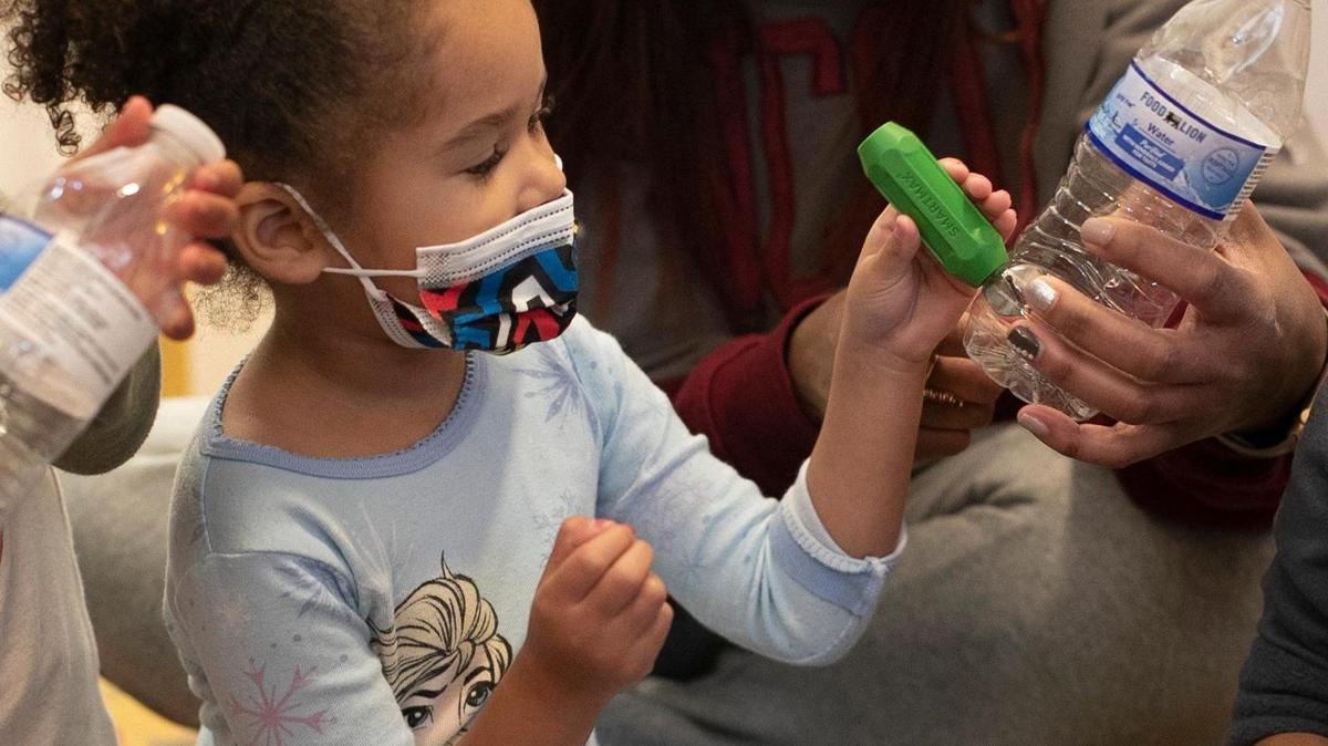 Teacher Nikki Pendleton shows three-year-old Ayla Adamas how to use a magnet to move a bell inside a plastic bottle during music class at A Safe Place Child Enrichment Center on Tuesday, December 20, 2022 in Raleigh, N.C.