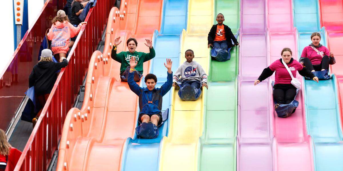 Fairgoers ride down the Big Apple slide at the N.C. State Fair in Raleigh, N.C., Sunday, Oct. 27, 2024.