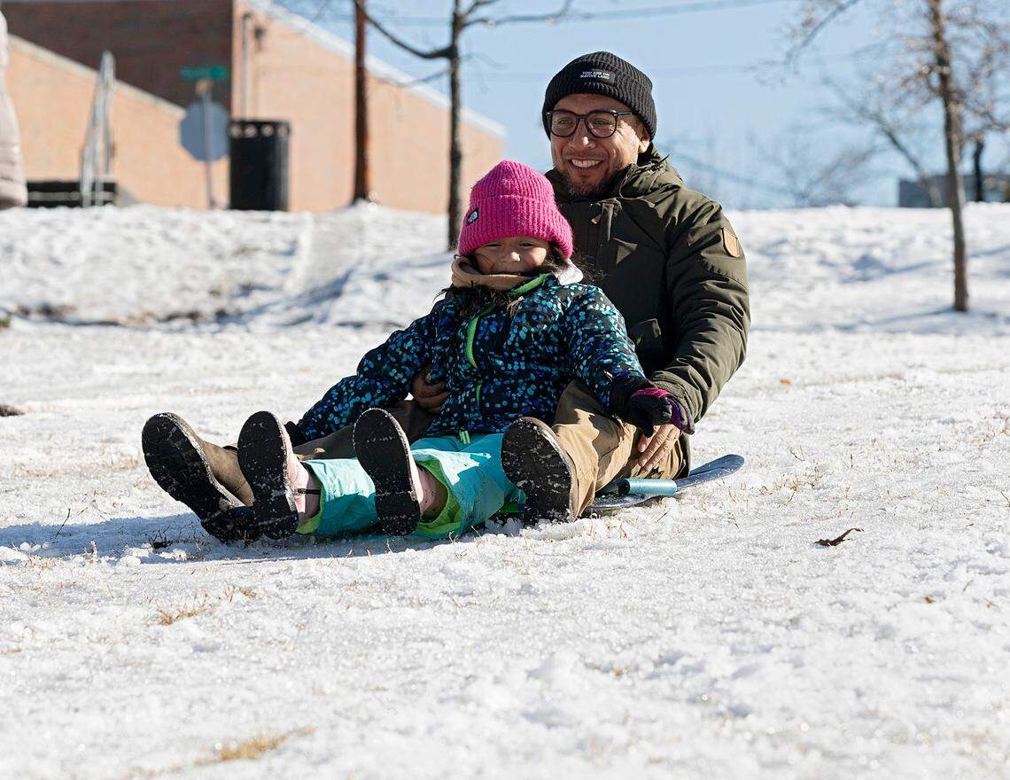Alex Hernandez sleds down a hill with his daughter, Kayla, 6, in Durham Central Park on Saturday, Jan. 11, 2025.