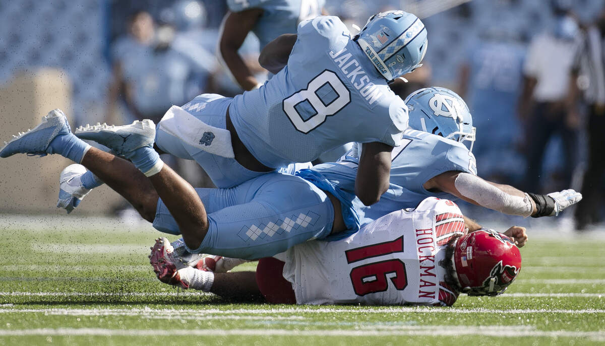 N.C. State quarterback Bailey Hockman (16) is sacked by North Carolina’s Chazz Surratt (21) and Khadry Jackson (8) in the fourth quarter at Kenan Stadium on Saturday, October 24, 2020 in Chapel Hill, N.C.