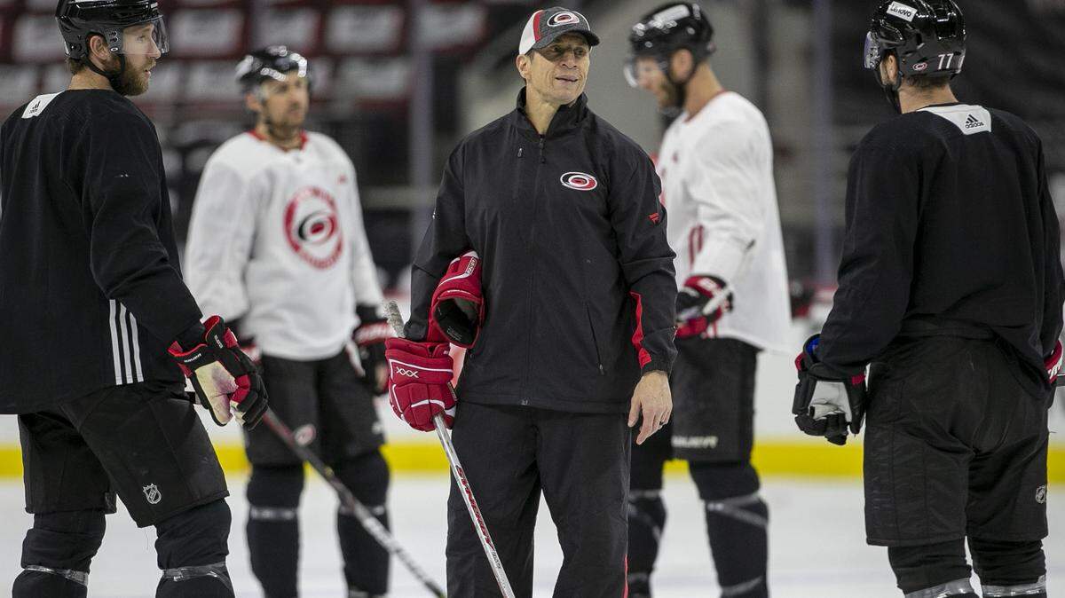 Carolina Hurricanes coach Rod Brind’Amour talks with players Jaccob Slavin (74) and Tony DeAngelo (77) during practice on Friday, May 13, 2022 as they prepare for game seven in the Stanley Cup first round series against Boston at PNC Arena in Raleigh, N.C.