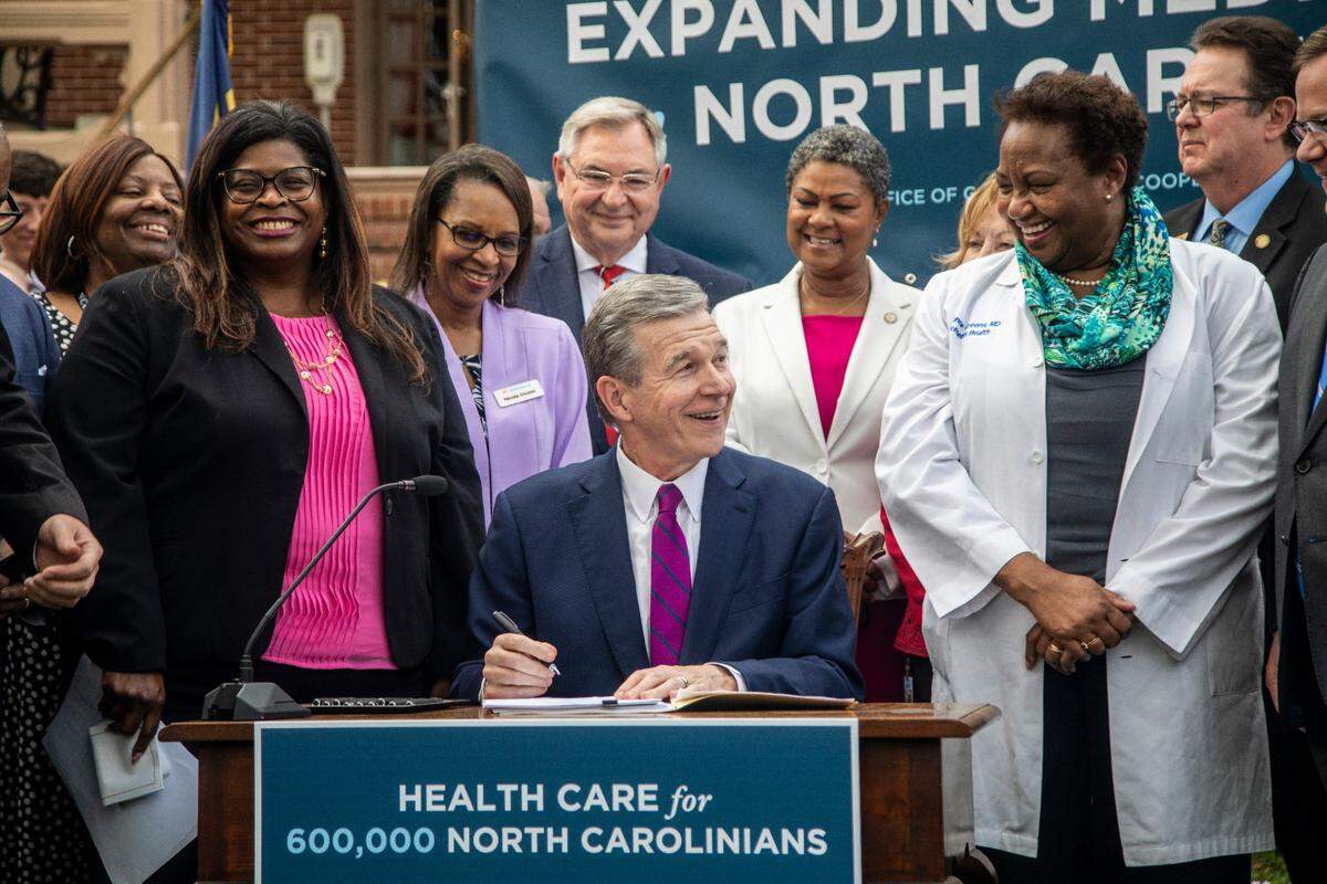 Gov. Roy Cooper signs a Medicaid expansion bill into law during a ceremony at the Executive Mansion on March 27, 2023.