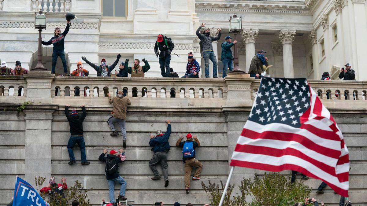 Rioters scale a wall at the U.S. Capitol on Jan. 6, 2021, in Washington.