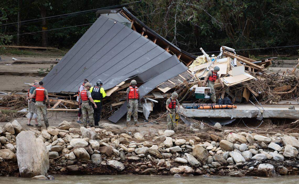 Two people and a dog are escorted to a rescue boat in Chimney Rock, N.C. on Sunday, September 29, 2024.