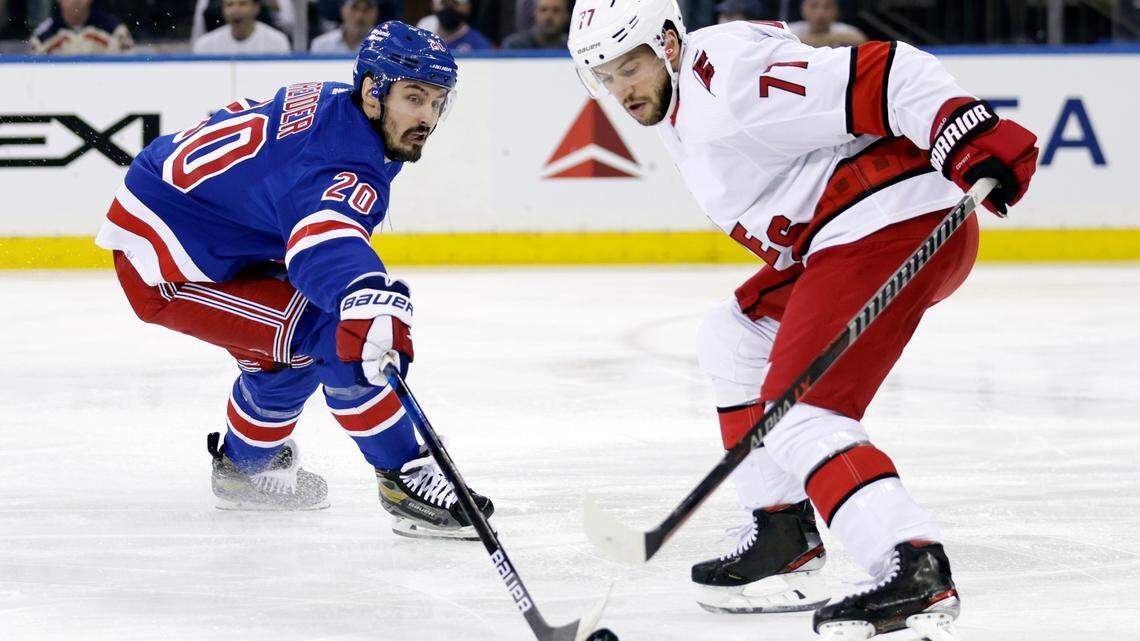 New York Rangers left wing Chris Kreider (20) knocks the puck away from Carolina Hurricanes defenseman Tony DeAngelo in the first period of Game 3 of an NHL hockey Stanley Cup second-round playoff series, Sunday, May 22, 2022, in New York.